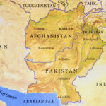 Paysage aride du Baloutchistan avec montagnes et villages isolés, illustrant l’immensité et l’isolement de cette région stratégique.