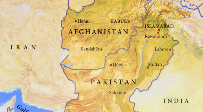 Paysage aride du Baloutchistan avec montagnes et villages isolés, illustrant l’immensité et l’isolement de cette région stratégique.