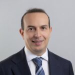 Portrait professionnel de Lamine Bougueroua, nouveau gérant dette émergente chez Carmignac, photographié en tenue formelle dans un environnement corporate. L’image met en avant une posture assurée et analytique, reflétant son expertise sur les marchés obligataires émergents. En arrière‑plan, un décor neutre ou un bureau moderne évoque un cadre institutionnel, renforçant l’idée de rigueur et de gestion active.