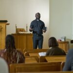 Salle de culte évangélique bondée en banlieue, fidèles en prière, ambiance musicale intense, symbolisant la concurrence religieuse dans les quartiers populaires.