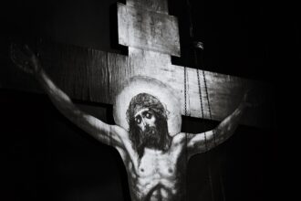 Image d’une église française au crépuscule, façade éclairée mais parvis désert, symbolisant un christianisme fragilisé. À l’arrière‑plan, silhouettes floues représentant les tensions entre héritage religieux, critiques culturelles et récupérations identitaires.