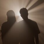 Silhouette d’un homme seul sous un réverbère dans une rue sombre, symbolisant l’ego face à ses ombres et la quête de lumière intérieure.