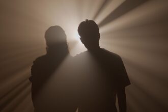 Silhouette d’un homme seul sous un réverbère dans une rue sombre, symbolisant l’ego face à ses ombres et la quête de lumière intérieure.