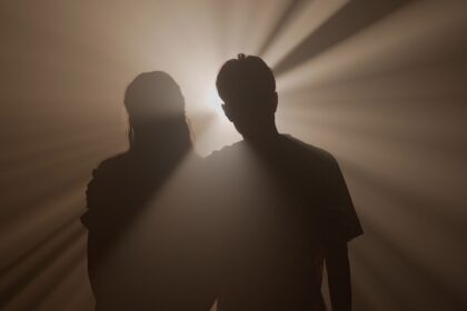 Silhouette d’un homme seul sous un réverbère dans une rue sombre, symbolisant l’ego face à ses ombres et la quête de lumière intérieure.
