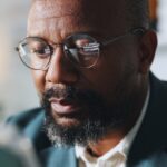 Une scène urbaine européenne en soirée, avec des silhouettes en discussion dans un café, symbolisant les réseaux diasporiques et les stratégies discrètes de recrutement menées par certains services de renseignement africains.