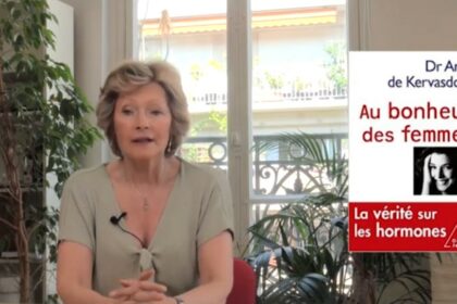 Portrait en lumière douce d’une femme d’une cinquantaine d’années, sereine, assise près d’une fenêtre. Le décor est épuré, évoquant la réflexion et la transmission. L’image suggère la maturité, la confiance et la quête d’informations fiables sur la ménopause.
