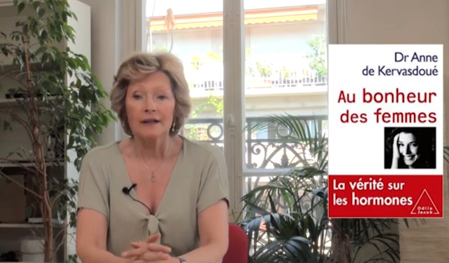 Portrait en lumière douce d’une femme d’une cinquantaine d’années, sereine, assise près d’une fenêtre. Le décor est épuré, évoquant la réflexion et la transmission. L’image suggère la maturité, la confiance et la quête d’informations fiables sur la ménopause.