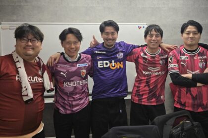 Photo de supporters réunis autour d’un écran diffusant un match de J‑League, partageant repas et analyses dans une ambiance conviviale.