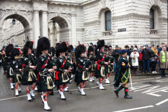 Défilé des Atholl Highlanders devant Blair Castle, avec soldats en tenue traditionnelle, drapeaux et cornemuses dans un cadre historique écossais.