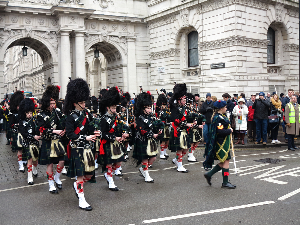 Défilé des Atholl Highlanders devant Blair Castle, avec soldats en tenue traditionnelle, drapeaux et cornemuses dans un cadre historique écossais.