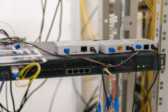 Illustration d’un routeur réseau entouré d’icônes de cybersécurité, symbolisant la décision de la FCC de restreindre les équipements étrangers.