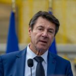 Portrait de Christian Estrosi lors d’un événement public, en arrière‑plan la ville de Nice, symbolisant la tension entre pouvoir municipal et ambition régionale.