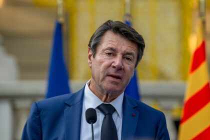 Portrait de Christian Estrosi lors d’un événement public, en arrière‑plan la ville de Nice, symbolisant la tension entre pouvoir municipal et ambition régionale.