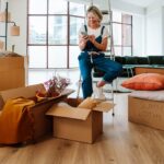 Personne préparant des cartons de déménagement dans un intérieur organisé, illustrant une transition bien planifiée.