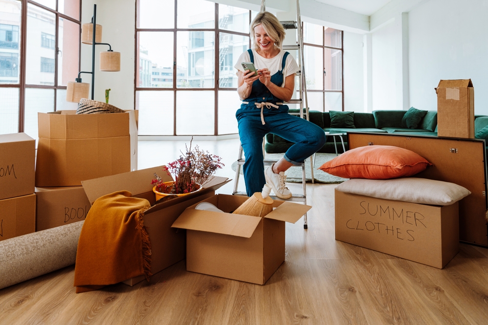 Personne préparant des cartons de déménagement dans un intérieur organisé, illustrant une transition bien planifiée.