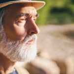 Portrait d’une personne âgée observant son reflet dans une lumière douce, illustrant la fragilité du corps et le sentiment d’invisibilité sociale.