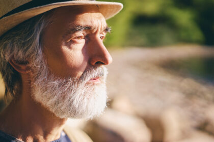 Portrait d’une personne âgée observant son reflet dans une lumière douce, illustrant la fragilité du corps et le sentiment d’invisibilité sociale.