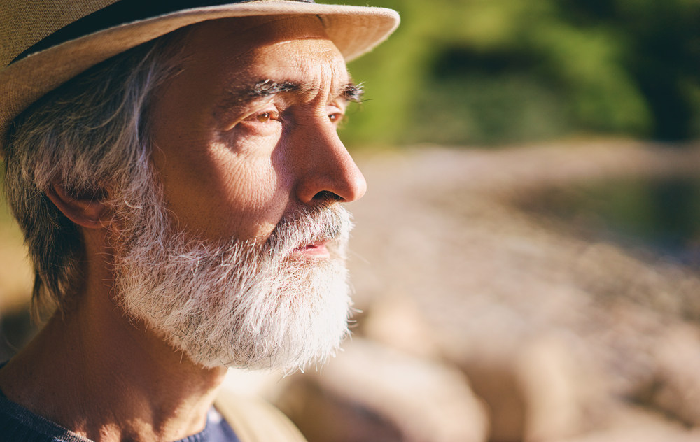 Portrait d’une personne âgée observant son reflet dans une lumière douce, illustrant la fragilité du corps et le sentiment d’invisibilité sociale.
