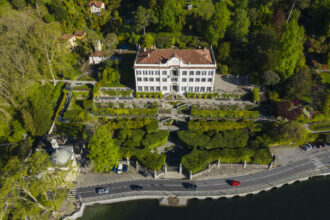 Vue de la Villa Carlotta entourée de jardins luxuriants, avec le lac de Côme en arrière‑plan et les terrasses fleuries qui mènent au musée.