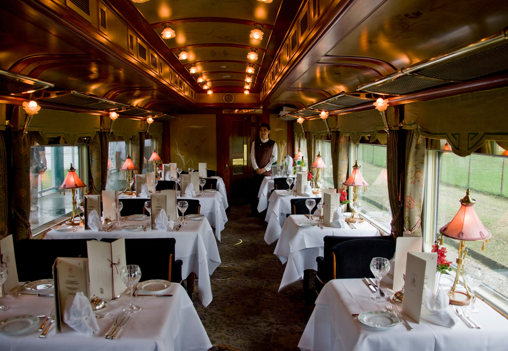 Intérieur raffiné d’un train de luxe Train de Prestige, avec boiseries élégantes, fauteuils confortables et ambiance haut de gamme évoquant le voyage d’exception.