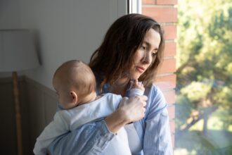 Portrait d’une mère seule avec son enfant dans un environnement urbain, illustrant la précarité croissante des familles monoparentales en France.