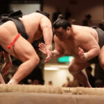 Lutteur de sumo dans le dohyō, accomplissant un rituel shinto ancestral, symbole de la tradition japonaise et de la spiritualité du sumo.