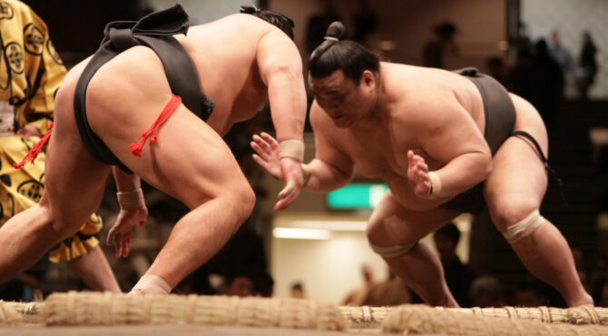 Lutteur de sumo dans le dohyō, accomplissant un rituel shinto ancestral, symbole de la tradition japonaise et de la spiritualité du sumo.