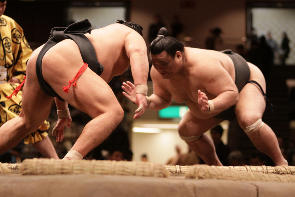 Lutteur de sumo dans le dohyō, accomplissant un rituel shinto ancestral, symbole de la tradition japonaise et de la spiritualité du sumo.